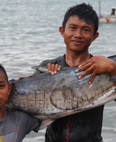 Image of a man and young boy holding up a large fish and smiling.