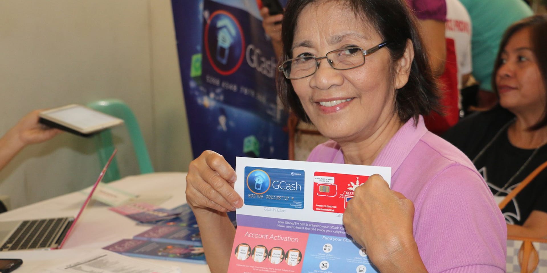 A woman smiling and holding up a letter containing an electronic payment card.