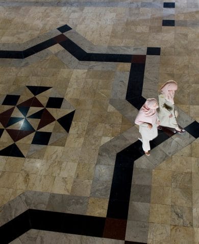 Overhead view of an intricately tiled floor with two women walking.