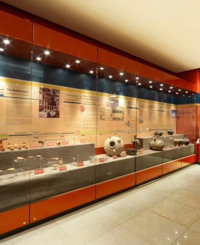 A museum exhibit with several examples f ancient pottery protected behind glass.