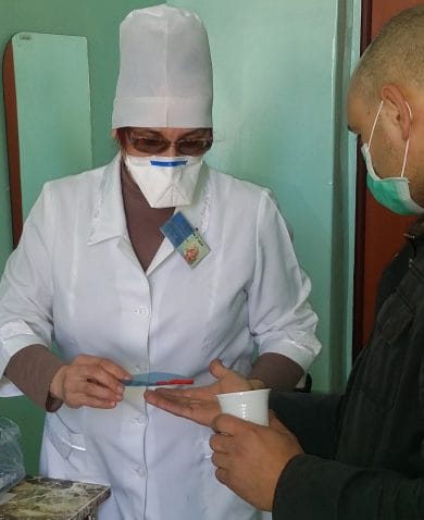 A healthcare worker providing medication in the form of pills to a patient.