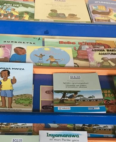 Several children's books lying face up on a blue shelf.