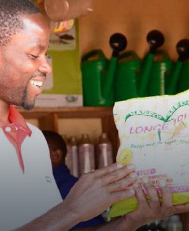 A man smiling as he holds a bag of seeds in a store.