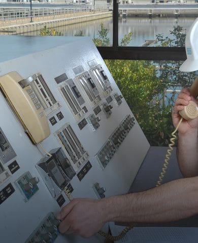 Image of a man in a hard hat operating a switchboard.
