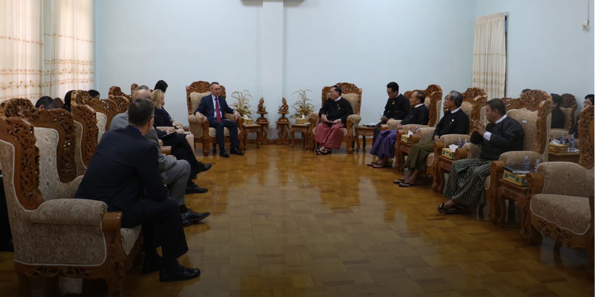 Image of several people in a circle, sitting in elegant chairs and having a discussion.