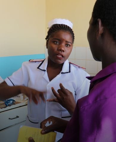 A healthcare worker speaking with a woman in a doctor's office.