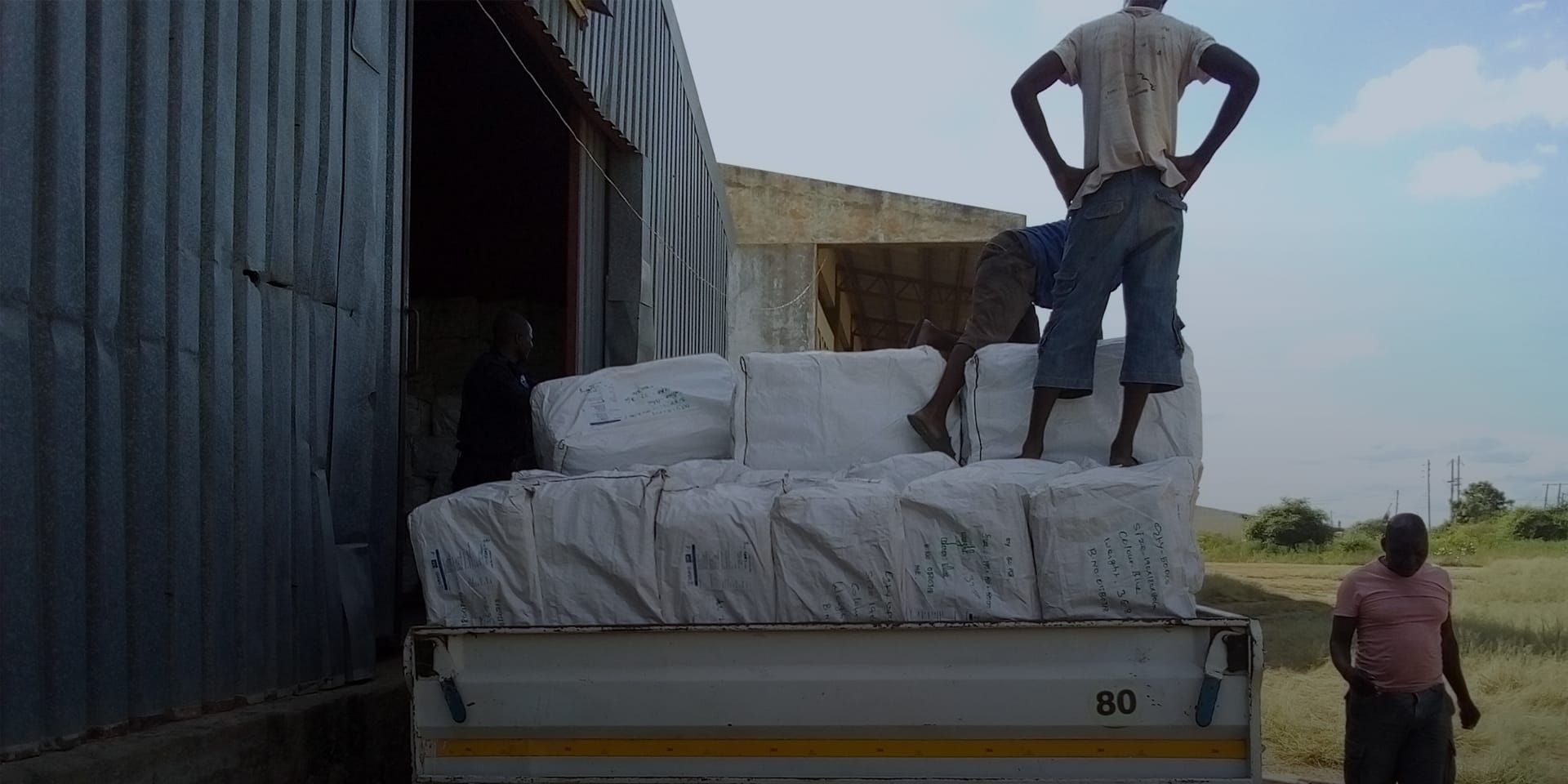 Image of workers unloading boxes on a truck into a warehouse.