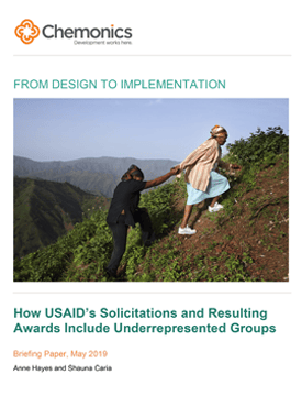 The front page of a report titled "rom Design to Implementation: How USAID’s Solicitations and Resulting Awards Include Underrepresented Groups." Includes image of two women walking up a steep hill.