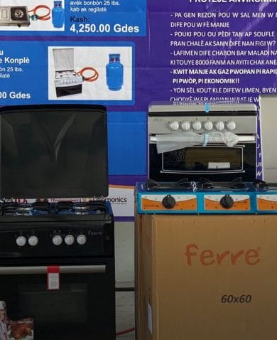 A woman wearing a protective mask stands beside several gas stoves on display in a store.