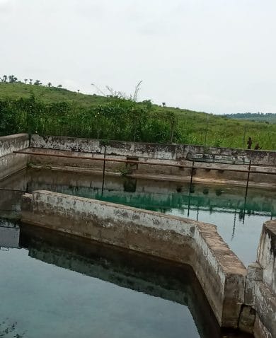 Image of a water reservoir with a person leaning over its wall and inspecting.