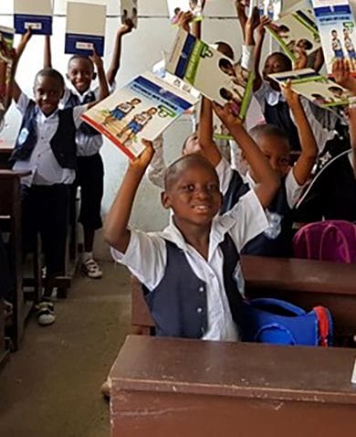 A group of children lift textbooks in the air happily