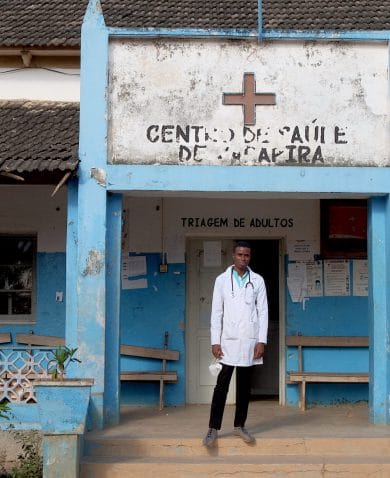A doctor posing for a photo in front of a clinic.