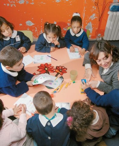 Children and their teacher sit around a table