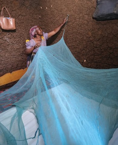 woman hanging a bednet over her bed