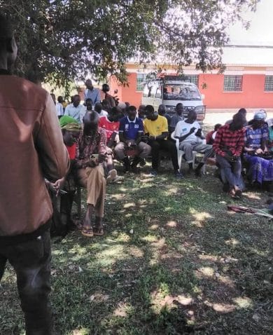 Village health team members meet outside in Uganda.